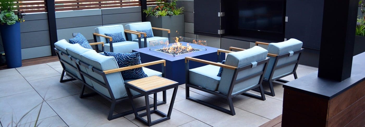 Patio with seating area around a square fire glass gas fire pit.