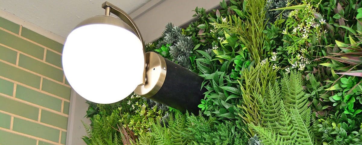 Outdoor lighting hung on a living wall of plants.