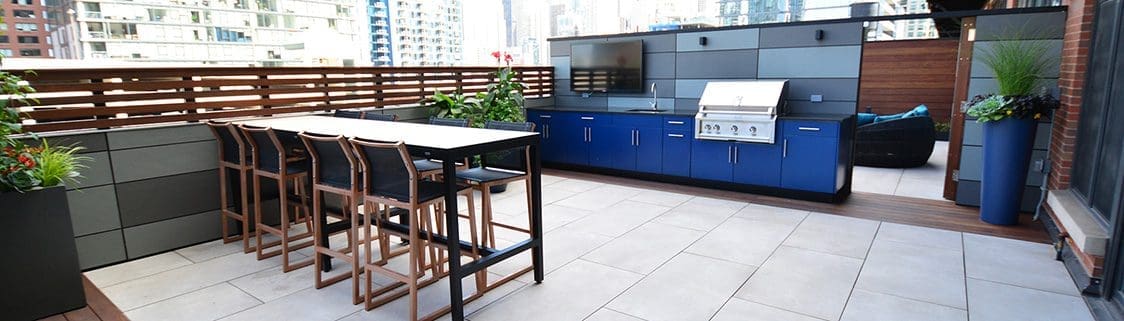 Large outdoor kitchen area with blue cabinets and a large bar-height table.