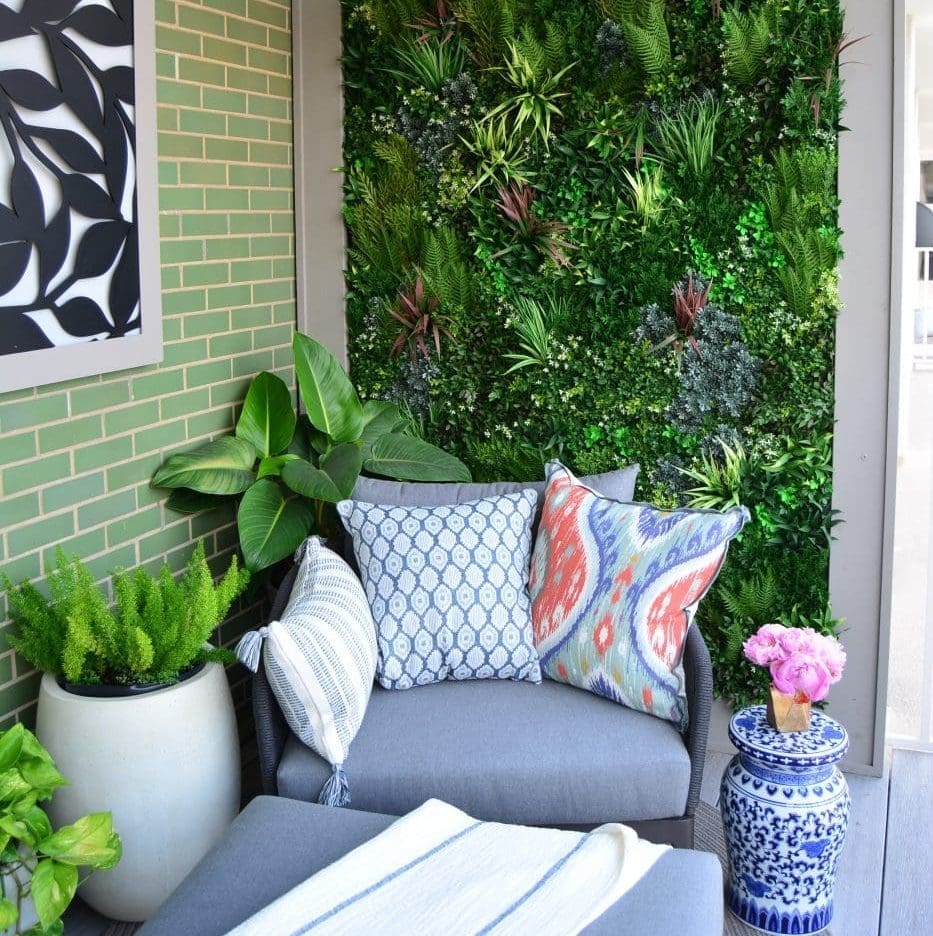 Outdoor chair with pillows next to a living greenery wall.